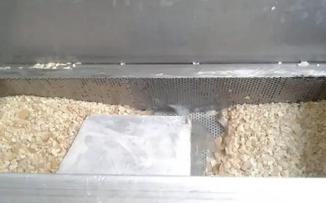 Drain sieve filled with calcium carbonate scale chips flushed from an EST tank